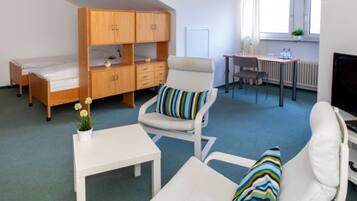 A compact room with a bunk bed, a desk, a chair, and a small table.