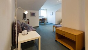 Une pièce comprenant un bureau, une chaise, une lampe et un petit meuble en bois.
