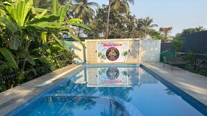 A swimming pool with a 'Welcome' sign and 'Villa The Caribbean Resort' logo. - Villa The Kinara Resort (Kihim)