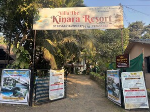 L’entrée de Villa The Kinara Resort, avec un panneau indiquant les coordonnées et les services proposés.