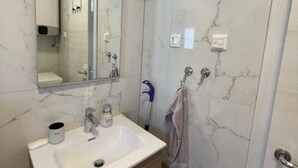 A bathroom with a marble sink, a mirror, a towel rack, and a shower area. - Apartment Rogoznica (Rogoznica)
