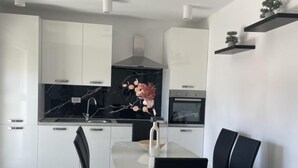 A modern kitchen with white cabinets, a black marble backsplash, and a built-in oven. - Apartment Rogoznica (Rogoznica)
