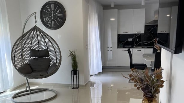 A modern living room with a hanging chair, a clock, a potted plant, and a vase with dried flowers. - Apartment Rogoznica (Rogoznica)