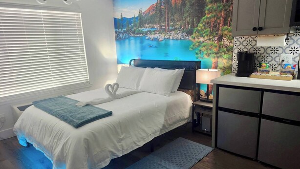 Ein Schlafzimmer mit Bett, Nachttisch, Lampe, Mikrowelle und Schrank.