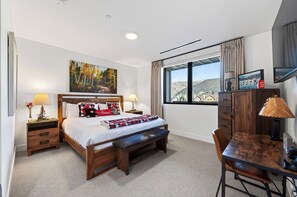 A bedroom with a bed, bedside tables, a desk, and a window with a view. - Condo + Ski Shuttle + Pool + Spa Access | Mountain Dream at Frontgate (Avon)