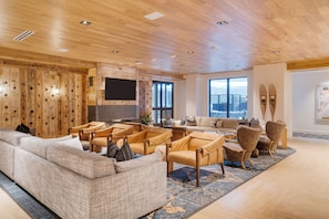A spacious living area with a wooden ceiling, a large sofa, multiple armchairs, and a television. - Condo + Ski Shuttle + Pool + Spa Access | Mountain Dream at Frontgate (Avon)
