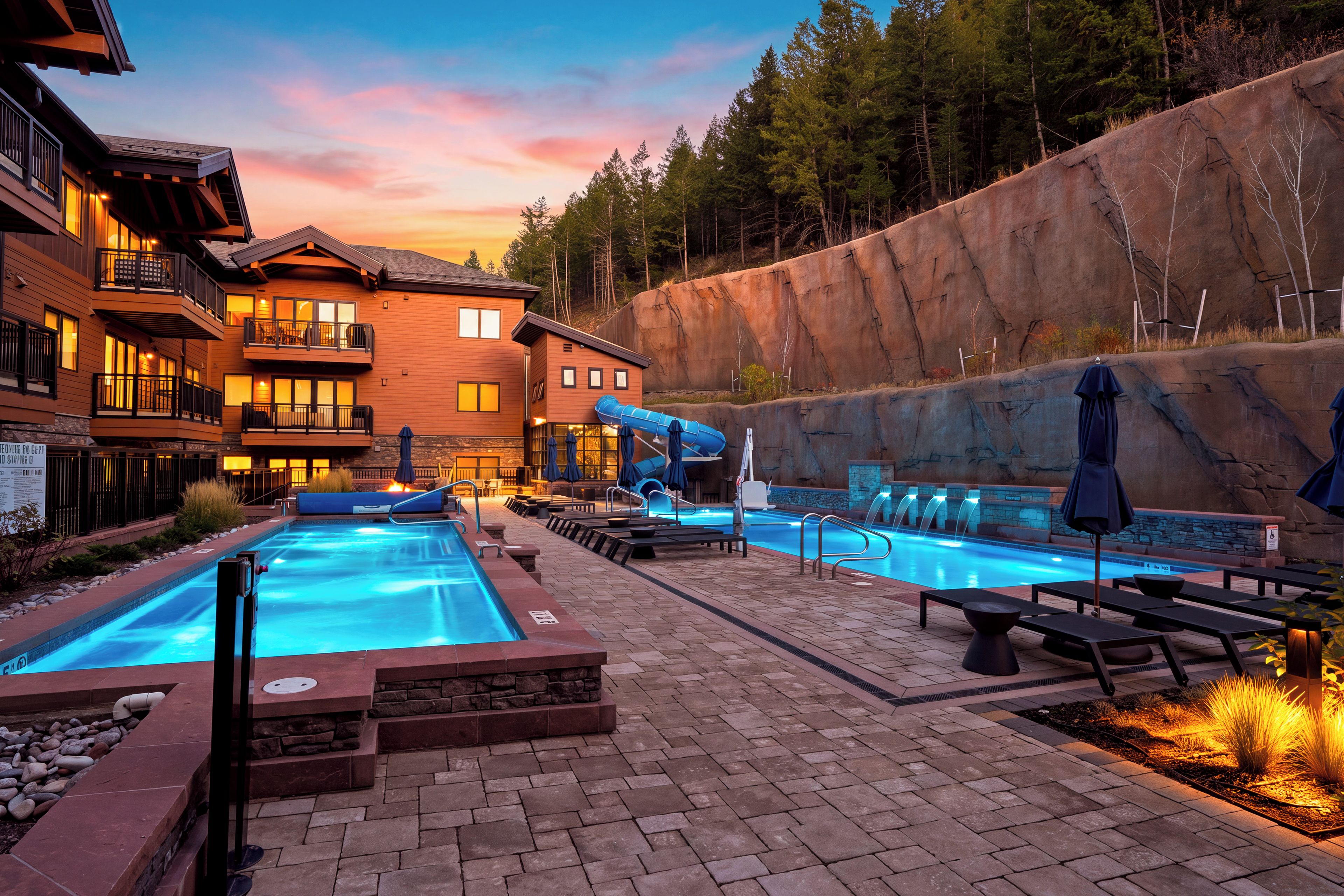 Ein Resort mit Schwimmbad, Liegestühlen und einer großen Felsformation.
