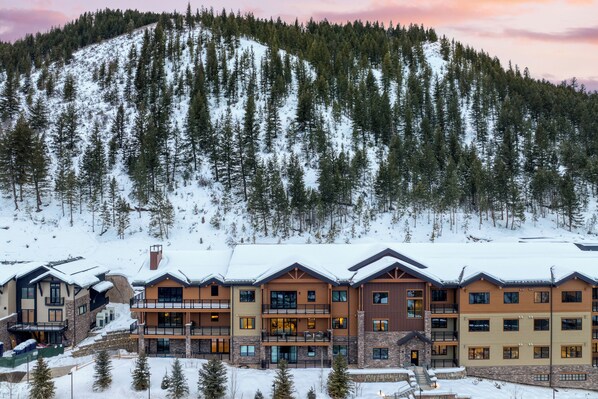 A multi-story hotel with balconies, a ski slope in the background, and snow-covered surroundings. - Condo + Ski Shuttle + Pool + Spa Access | Mountain Dream at Frontgate (Avon)