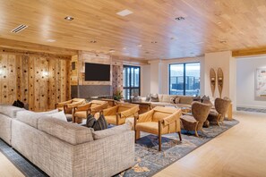 A spacious living area with a wooden ceiling, a large sofa, several armchairs, and a television. - Condo + Ski Shuttle + Pool + Spa Access | Mountain Dream at Frontgate (Avon)