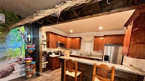A kitchen with wooden cabinets, a microwave, a refrigerator, and a bar area with two stools. - Tropical Spa Studio, Jacuzzi, Kitchen, Sparks (Sparks)