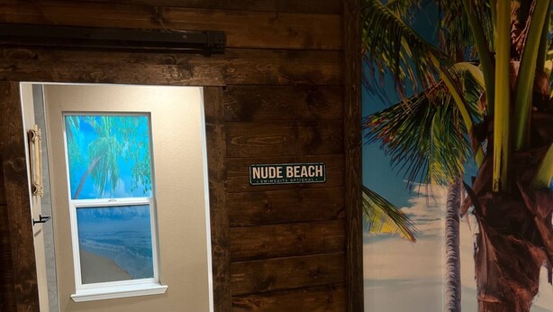 A wooden door with a sign reading "NUDE BEACH" and a mural of a palm tree. - Tropical Spa Studio, Jacuzzi, Kitchen, Sparks (Sparks)