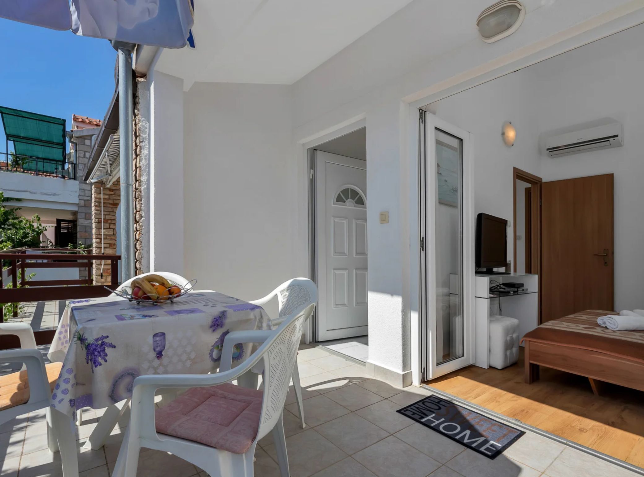 A small, clean room with a bed, a TV, and a door leading to a balcony.