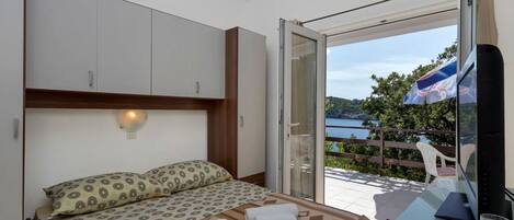 Un dormitorio con una cama, un escritorio y vistas a un balcón con mesa y sillas.