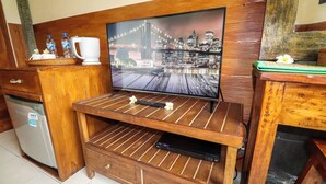 Uma unidade de entretenimento de madeira com televisão, um frigorífico pequeno e uma máquina de café.