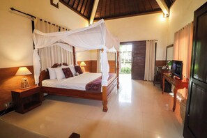 A four-poster canopy bed with a wooden frame and white bedding, a bedside table with a lamp, and a television on a wooden stand. - Ubud Garden View Suite Relaxing Pool Stay (Kecamatan Ubud)
