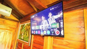A television mounted on a wooden wall displaying a streaming service interface with various content options. - Ubud Nature Escape Bungalow ricefield view (Kecamatan Ubud)