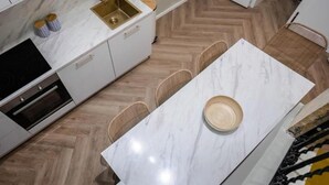 Eine moderne Küche mit Marmorarbeitsplatte, einer goldenen Spüle und einem eingebauten Backofen.