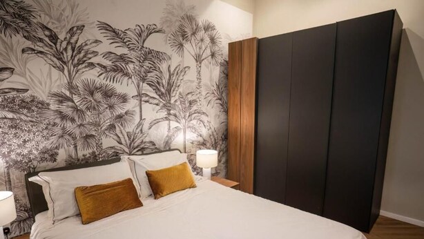 Ein Schlafzimmer mit einem Bett, zwei Kissen, einem Nachttisch mit Lampe und einem Kleiderschrank.