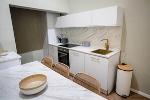 A compact kitchen with white cabinets, a marble countertop, a built-in oven, and a sink with a gold faucet. - RUWTS Valletta Central Maisonette (Il-Belt Valletta)