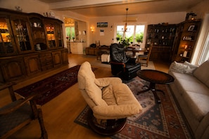 A living room with a sofa, armchair, and a dining area with a table and chairs.