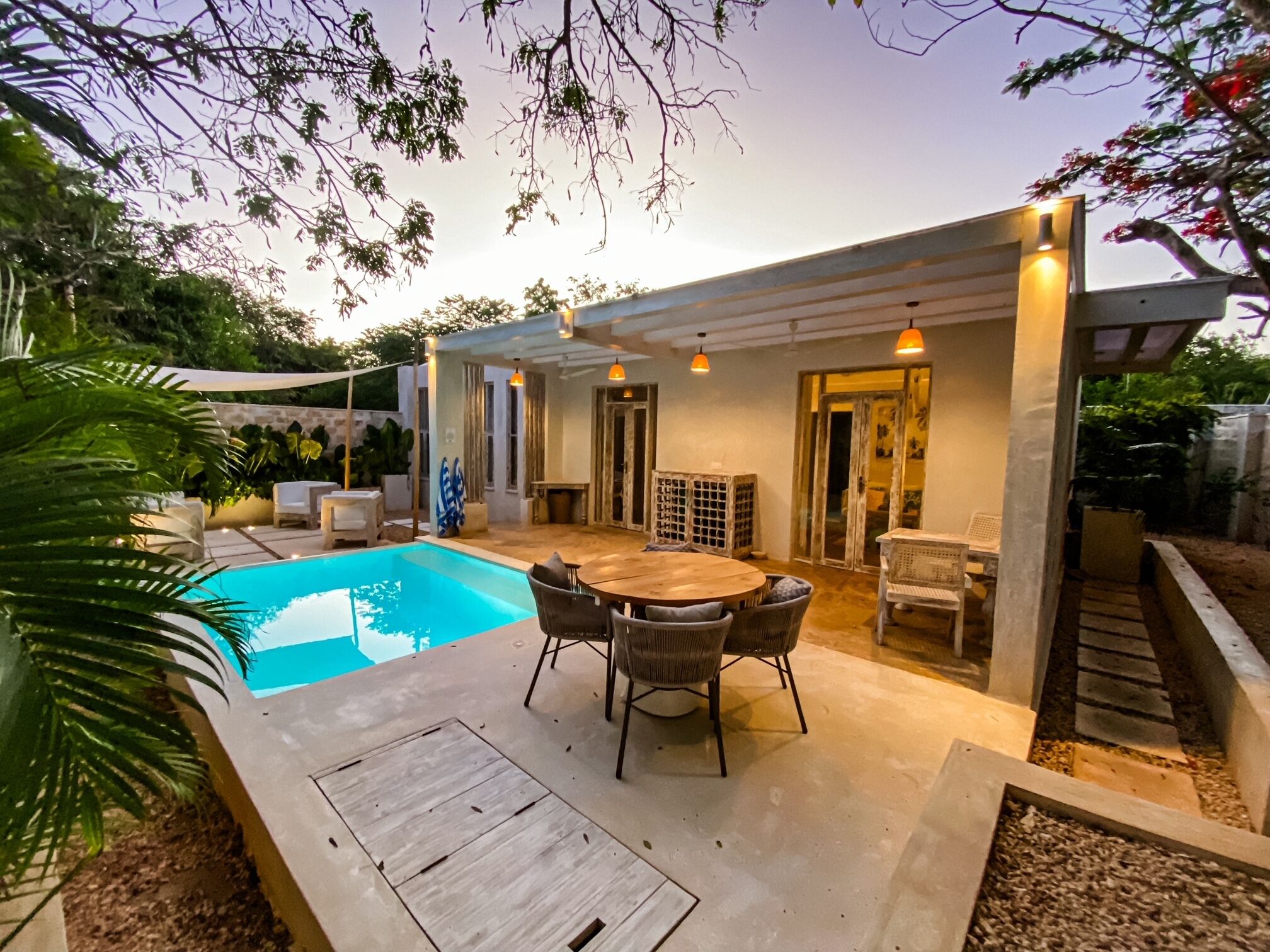 A covered outdoor area with a pool, seating, and a pergola.