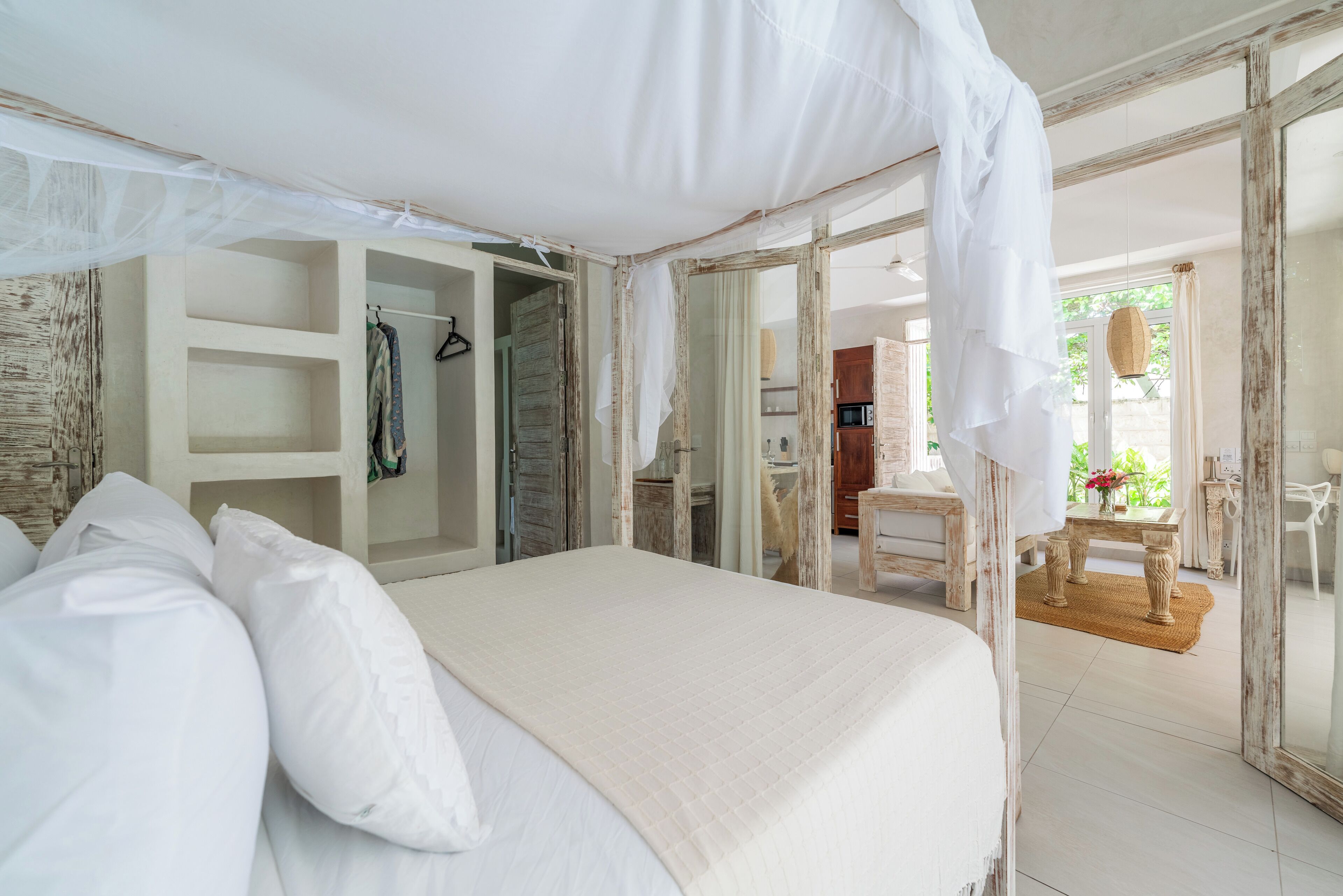 A bedroom with a canopy bed, a walk-in closet, and a view of the outdoor dining area.