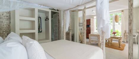 A bedroom with a canopy bed, a walk-in closet, and a view of the outdoor dining area.