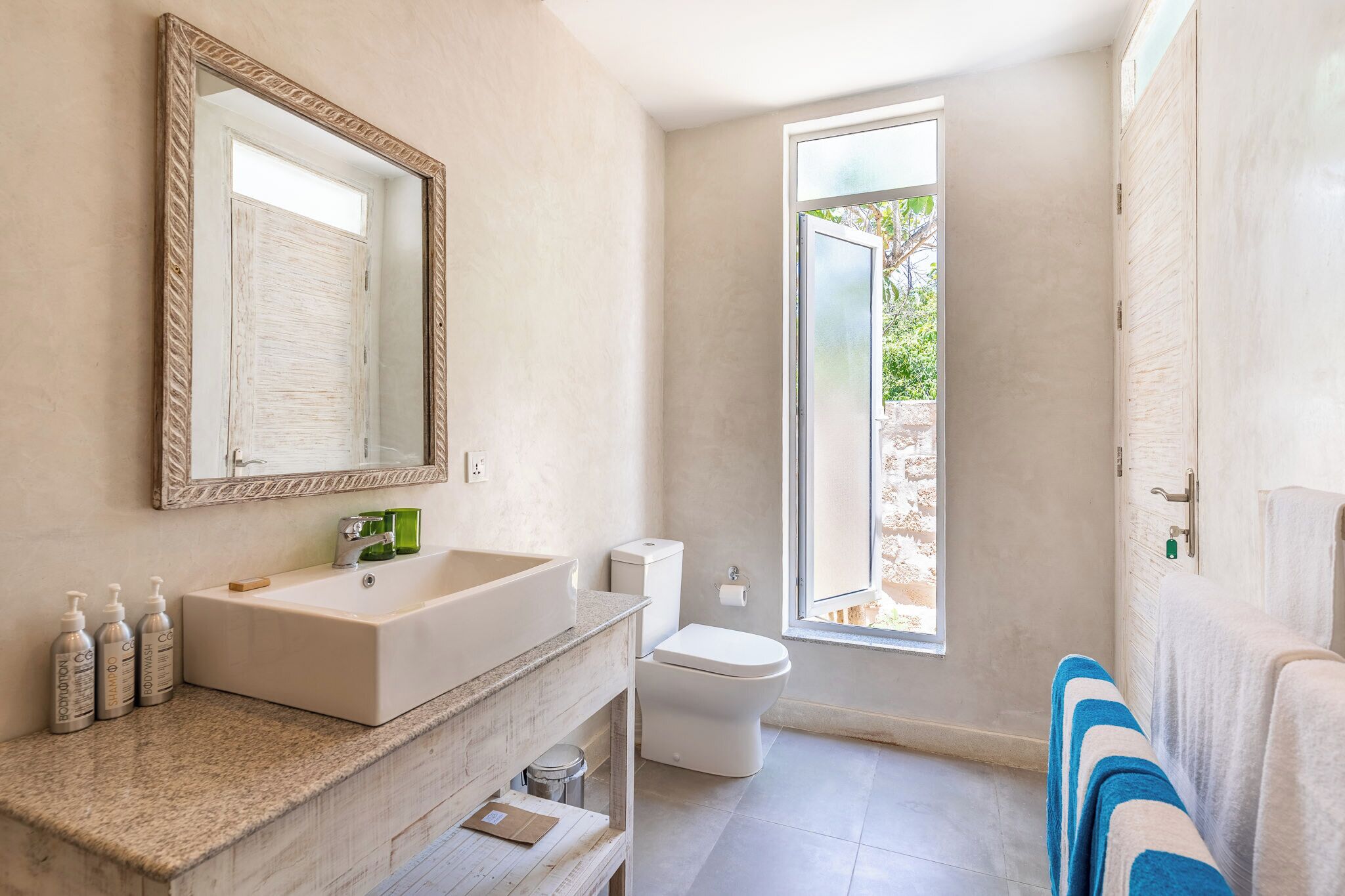 A modern bathroom with a large mirror, a rectangular sink, and a toilet.