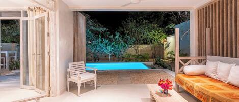 An open-plan living area with a pool, a ceiling fan, and a sofa.