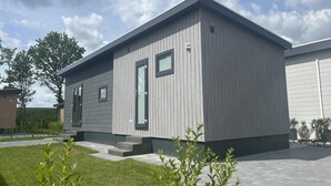 Een modern, laag gebouw met een grijze gevel, een deur en een klein raam.
