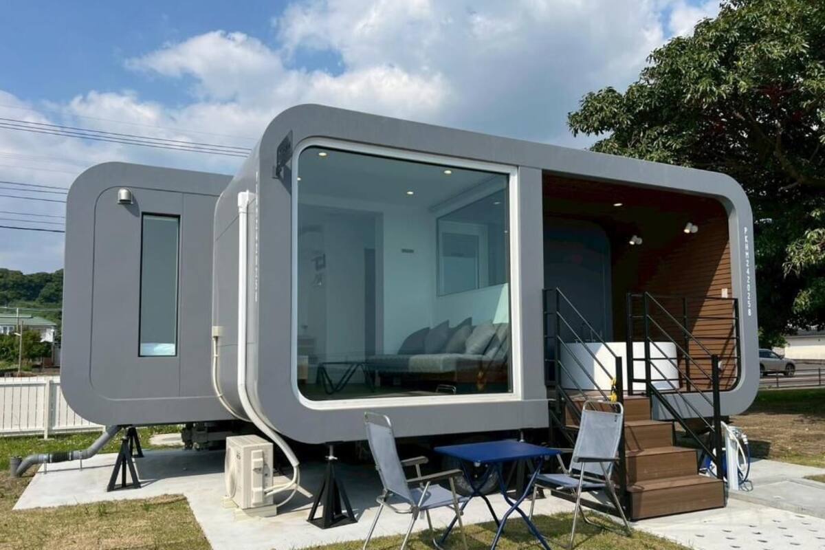 Two modern, compact mobile homes with large windows, a staircase, and outdoor seating.