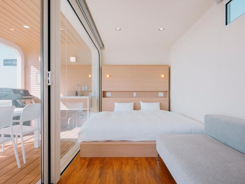 Una habitación de hotel moderna con una cama, un sofá y un ventanal de vidrio que da a un espacio exterior.
