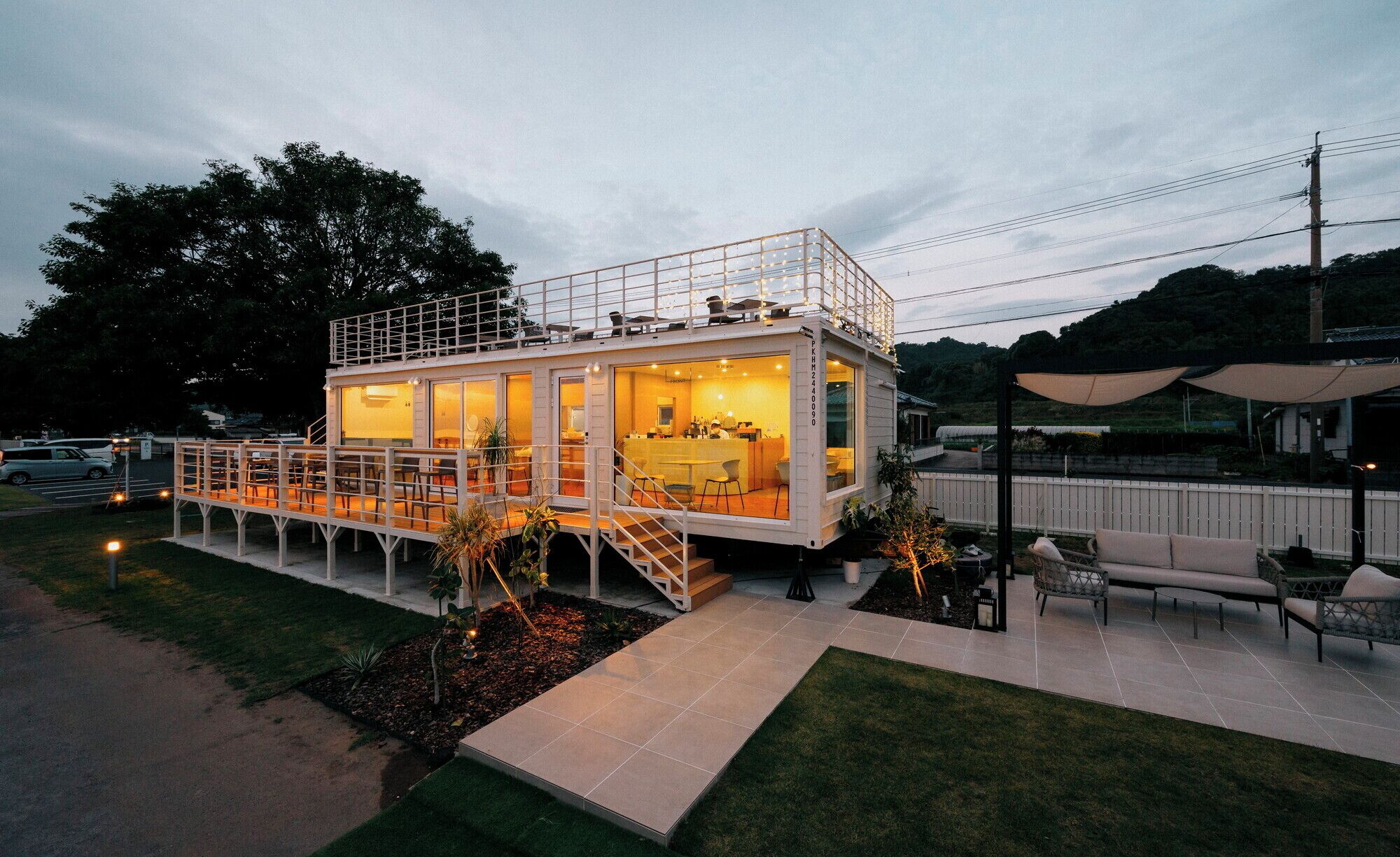 A modern, two-story house with a balcony and a patio area.