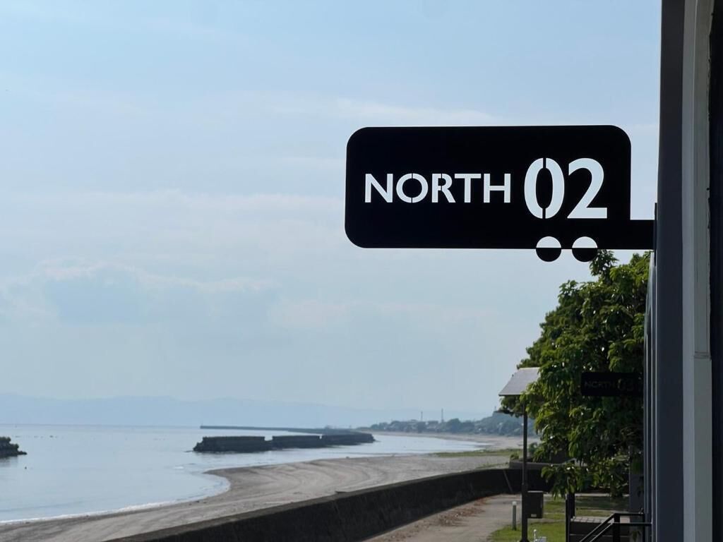 Un panneau indiquant « NORD 02 », avec en arrière-plan une plage et une jetée.