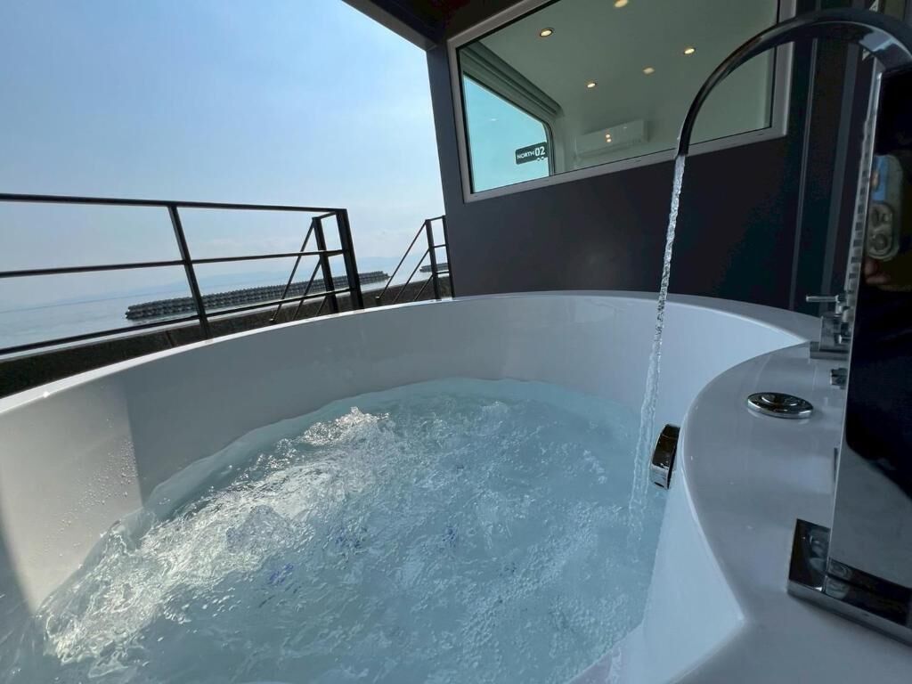 Un bain à remous avec de l’eau en circulation, une rambarde en métal et une vue sur la mer.
