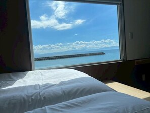 Uma cama com vista para o mar pela janela.