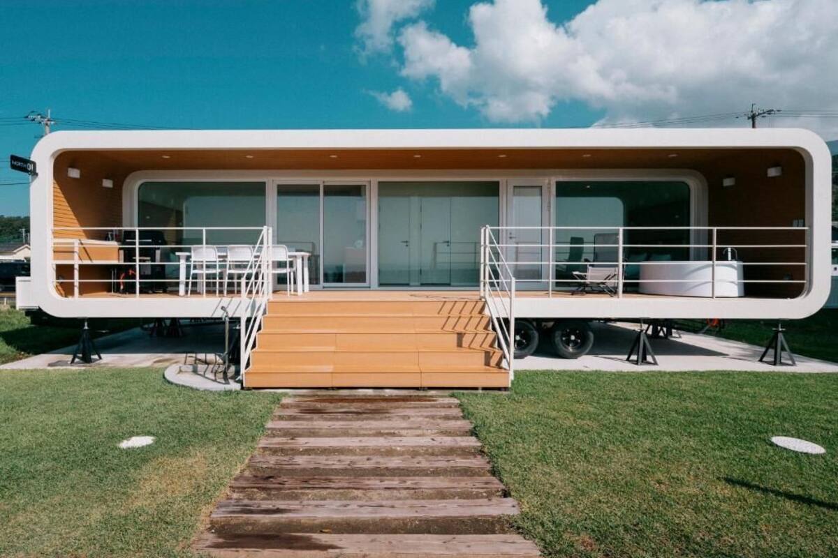 A modern, single-story building with a wooden deck, glass doors, and a ramp leading to the entrance.