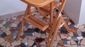 Ein Holzhocker mit einer an der Rückenlehne befestigten Ablage, platziert auf einem Mosaikfliesenfußboden.