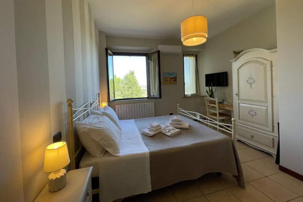 Une chambre à coucher comprenant un lit, une lampe de chevet, une fenêtre, une armoire et une suspension.