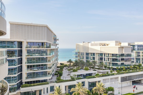 A modern multi-story building with balconies overlooking a beach. - Bloomfields 2br+1 in Ajwan Towers (Abu Dhabi)