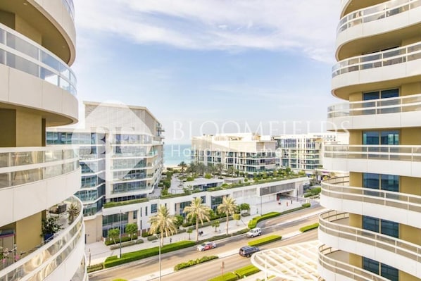 A modern multi-story residential building with balconies, a landscaped rooftop garden, and a clear view of the surrounding area.