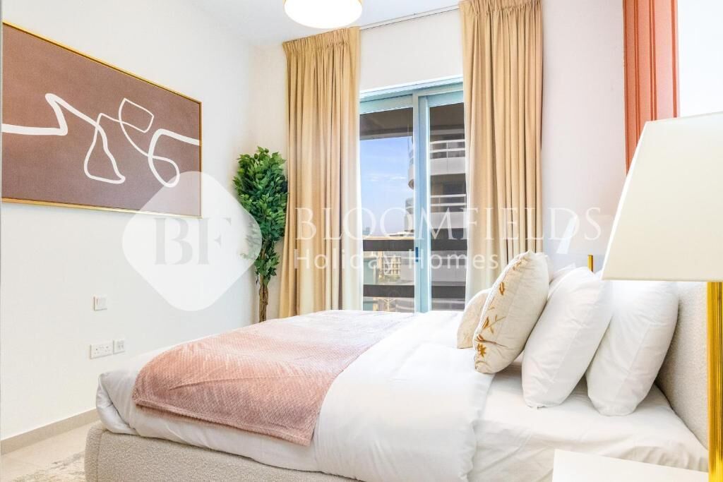 Ein modernes Schlafzimmer mit einem großen Bett, cremefarbenen Vorhängen, Blick durch eine Glastür und einem an der Wand befestigten abstrakten Kunstwerk.