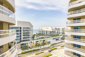 A modern multi-story residential building with balconies, a landscaped rooftop garden, and a view of the sea. - Bloomfields 2br+1 in Ajwan Towers (Abu Dhabi)