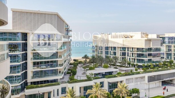 A modern multi-story hotel with a glass facade, outdoor terraces, and a view of the sea. - Bloomfields 2br Unique Ajwan Soul B (Abu Dhabi)
