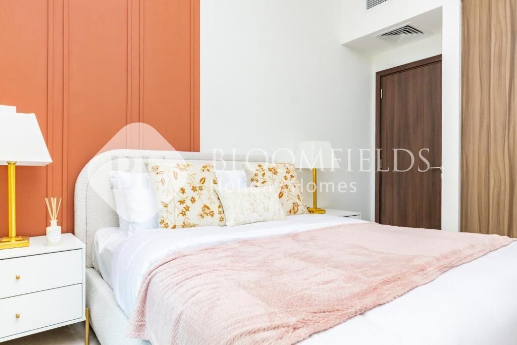 A neatly arranged bedroom with a bed, bedside table, lamp, and a door.
