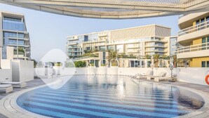 A modern hotel with a large outdoor swimming pool, multiple balconies, and a contemporary architectural design. - Bloomfields 2br Unique Ajwan Soul B (Abu Dhabi)
