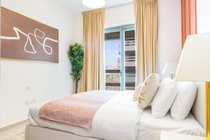 A hotel room with a bed, a large window with curtains, a potted plant, and a wall-mounted artwork. - Bloomfields 2br+1 in Ajwan Towers (Abu Dhabi)