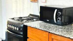 A kitchen with a stove, oven, microwave, and wooden cabinets. - Liora Haven - 2BR Home That Feels Just Right (Arusha)