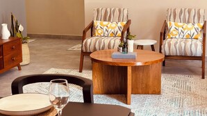 A dining area with a round wooden table, two chairs with patterned cushions, a vase, and a framed picture on the wall. - Liora Haven - 2BR Home That Feels Just Right (Arusha)