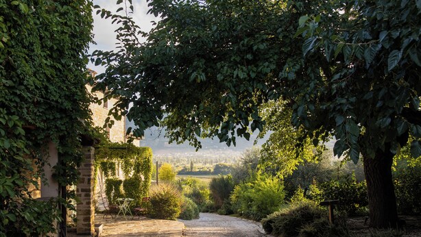Un chemin de pierres qui traverse un jardin et offre une vue sur un village situé au loin.